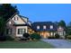 Charming home featuring manicured lawn, stone accents, and inviting entryway with a well-lit portico at dusk at 154 Gold Leaf Trail Trl, Powder Springs, GA 30127