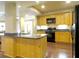 Open kitchen featuring warm wood cabinets, black appliances, granite countertops and kitchen island at 154 Gold Leaf Trail Trl, Powder Springs, GA 30127