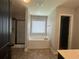 Bright bathroom featuring a soaking tub, shower, window, and dark door at 443 Strawberry Walk, Loganville, GA 30052
