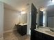 Double vanity sinks, mirrors, and a dark colored door leading to the bathtub and shower area at 443 Strawberry Walk, Loganville, GA 30052