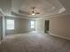 Spacious main bedroom with tray ceiling, ceiling fan, carpeted floor, and natural light from the windows at 443 Strawberry Walk, Loganville, GA 30052