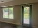 Neutral living room with large window and exterior door featuring blinds for natural light and privacy at 443 Strawberry Walk, Loganville, GA 30052