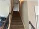 Carpeted stairs with dark wood railing lead to the upper level at 443 Strawberry Walk, Loganville, GA 30052