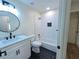 A sleek bathroom with black and white tile, a shower with tub, and round mirror above the sink at 705 Stewart Nw Cir, Marietta, GA 30064