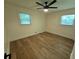 A light and airy bedroom featuring two windows, modern ceiling fan and light, and beautiful wood laminate flooring at 705 Stewart Nw Cir, Marietta, GA 30064