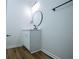 Bathroom featuring a sleek white vanity with a round black framed mirror, wood look flooring and matte black fixtures at 90 Ayers Rd, Bowdon, GA 30108