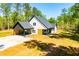 Charming white farmhouse-style home with a modern design, nestled among lush trees and greenery at 90 Ayers Rd, Bowdon, GA 30108