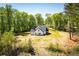 Rear view of new construction white farmhouse featuring black roof and surrounded by a lush tree line at 90 Ayers Rd, Bowdon, GA 30108