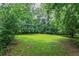 Picture of a large, grassy backyard surrounded by green trees at 1744 Cum Laude Way, Lawrenceville, GA 30044