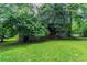 Exterior view of home with a large grassy backyard and mature trees at 1744 Cum Laude Way, Lawrenceville, GA 30044