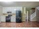 View of kitchen with black appliances, tile floor, and stairway access at 1744 Cum Laude Way, Lawrenceville, GA 30044
