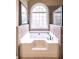 Soaking tub with tiled surround and a large arched window allowing lots of natural light at 893 Somersby Dr, Dallas, GA 30157