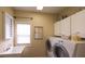 Bright laundry room with a utility sink, white cabinets, and modern appliances at 893 Somersby Dr, Dallas, GA 30157