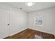 A minimalist bedroom featuring hardwood floors and a sunlit window with a door to the side at 1833 Flat Shoals Se Rd, Atlanta, GA 30316