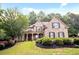 Charming brick home featuring a manicured lawn, dark wood shutters, and a welcoming front porch with stone columns at 208 Grandmar, Canton, GA 30115