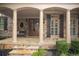 Inviting front porch with stone pillars, double doors, and a cozy bench, complemented by meticulously maintained landscaping at 208 Grandmar, Canton, GA 30115