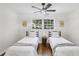 Neutral bedroom featuring two beds, wood floors, large window, and ceiling fan at 2436 Ovidia Sw Cir, Atlanta, GA 30311