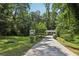 Long driveway leading to a quaint two-story home surrounded by mature trees at 2436 Ovidia Sw Cir, Atlanta, GA 30311