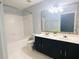 Bathroom showcasing a double sink vanity, decorative mirror, and a tiled tub-shower combination at 4645 Valais Ct # 10, Johns Creek, GA 30022