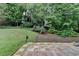 Manicured backyard featuring a lawn, brick patio, mulch beds and mature trees at 5015 Riverthur Pl, Peachtree Corners, GA 30096