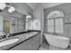 Stylish bathroom features a double granite vanity, soaking tub, arched window, and frameless shower at 5015 Riverthur Pl, Peachtree Corners, GA 30096