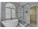 Elegant bathroom showcases a soaking tub, a frameless shower, and an arched window at 5015 Riverthur Pl, Peachtree Corners, GA 30096