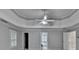 Open bedroom featuring neutral gray walls, a tray ceiling, a ceiling fan, and multiple closets at 5015 Riverthur Pl, Peachtree Corners, GA 30096