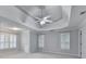 Spacious primary bedroom with tray ceilings, a ceiling fan, and natural light from shuttered windows at 5015 Riverthur Pl, Peachtree Corners, GA 30096