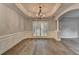 Elegant dining room with hardwood floors, coffered ceiling, wainscoting, chandelier, and large window at 5015 Riverthur Pl, Peachtree Corners, GA 30096