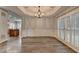 Light-filled dining area with hardwood floors, tray ceiling, chandelier, wainscoting, and plantation shutters at 5015 Riverthur Pl, Peachtree Corners, GA 30096