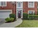 Close-up of a home's front entrance with decorative door, manicured landscaping, and brick facade at 5015 Riverthur Pl, Peachtree Corners, GA 30096