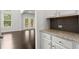 Kitchen with granite counters, stainless appliances, and tile backsplash opens to a light-filled living space at 5575 Mirror Lake Dr, Cumming, GA 30028