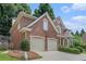 Two-car garage with traditional brick exterior, white doors and trim, and manicured landscaping at 5003 Village Terrace Dr, Dunwoody, GA 30338