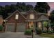 Charming brick home at twilight featuring manicured landscaping and a two-car garage at 5003 Village Terrace Dr, Dunwoody, GA 30338
