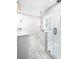 This bathroom boasts bright natural light, marble floors and a frameless shower at 8175 Main St, Woodstock, GA 30188