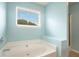Bright bathroom featuring a soaking tub under a window, next to a glass enclosed shower at 126 Wellbrook Ne Ct, Conyers, GA 30012