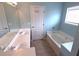 Bright bathroom featuring a double vanity, soaking tub, and a window that provides natural light at 126 Wellbrook Ne Ct, Conyers, GA 30012