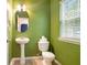Bright half bathroom with green walls, pedestal sink, and natural light from a window at 126 Wellbrook Ne Ct, Conyers, GA 30012