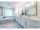 Main bathroom features a large tub with marble tile surround, dual sink vanity, and a glass enclosed shower at 1542 Idlewood Rd, Tucker, GA 30084