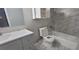 Well-lit bathroom with gray tiles, toilet, shower with tub, vanity, and mirror at 2035 Northland Dr, Lawrenceville, GA 30044