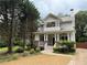 Charming two-story home featuring a welcoming front porch with brick and white pillars, manicured lawn and driveway at 2552 White Oak Dr, Decatur, GA 30032