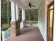Inviting porch featuring brick and white pillars, wood flooring, a ceiling fan, and a glimpse of the outdoor scenery at 2552 White Oak Dr, Decatur, GA 30032