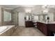 Luxurious bathroom featuring a soaking tub, glass shower, and dark wood cabinets with granite countertops at 4665 Idlewood Dr, Cumming, GA 30040