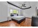 Bright bedroom with tray ceiling, ceiling fan, large window, hardwood floors and modern furnishings at 630 Birch River Ln, Lawrenceville, GA 30043