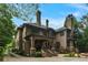 Elegant brick home with multiple chimneys, a covered front porch, a gated driveway, and manicured landscaping at 1640 Nottingham Ne Way, Atlanta, GA 30309