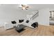 Bright living room with hardwood floors, black accents, a large sofa, and a staircase at 116 Eleanora Park, Loganville, GA 30052