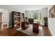Well-lit office with built-in bookshelves, bay window, and wood desk on a patterned rug at 3445 Strawberry Ln, Cumming, GA 30041