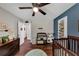 Bedroom featuring blue accent wall, dark wood crib, changing table, wood floors, and ceiling fan at 1050 Birdseye Vw, Locust Grove, GA 30248