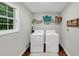Laundry room featuring washer, dryer, shelving, window, and wood floor at 1050 Birdseye Vw, Locust Grove, GA 30248