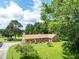 Lush lawns surround a beautiful brick house, enhanced by the view of trees under a bright sky at 1502 Campground Rd, Mcdonough, GA 30252